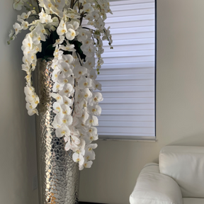 Kaskadierende Phalaenopsis-Orchideen in extrahoher gehämmerter Vase